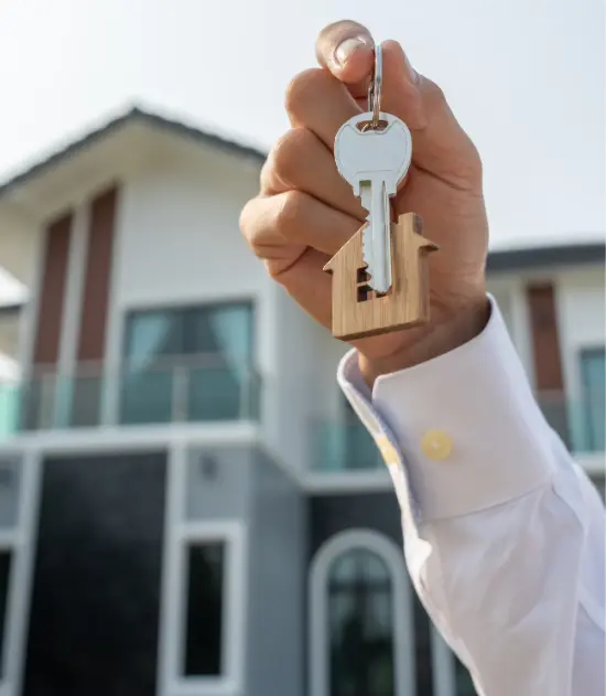 Image of a person holding keys in front of a house.